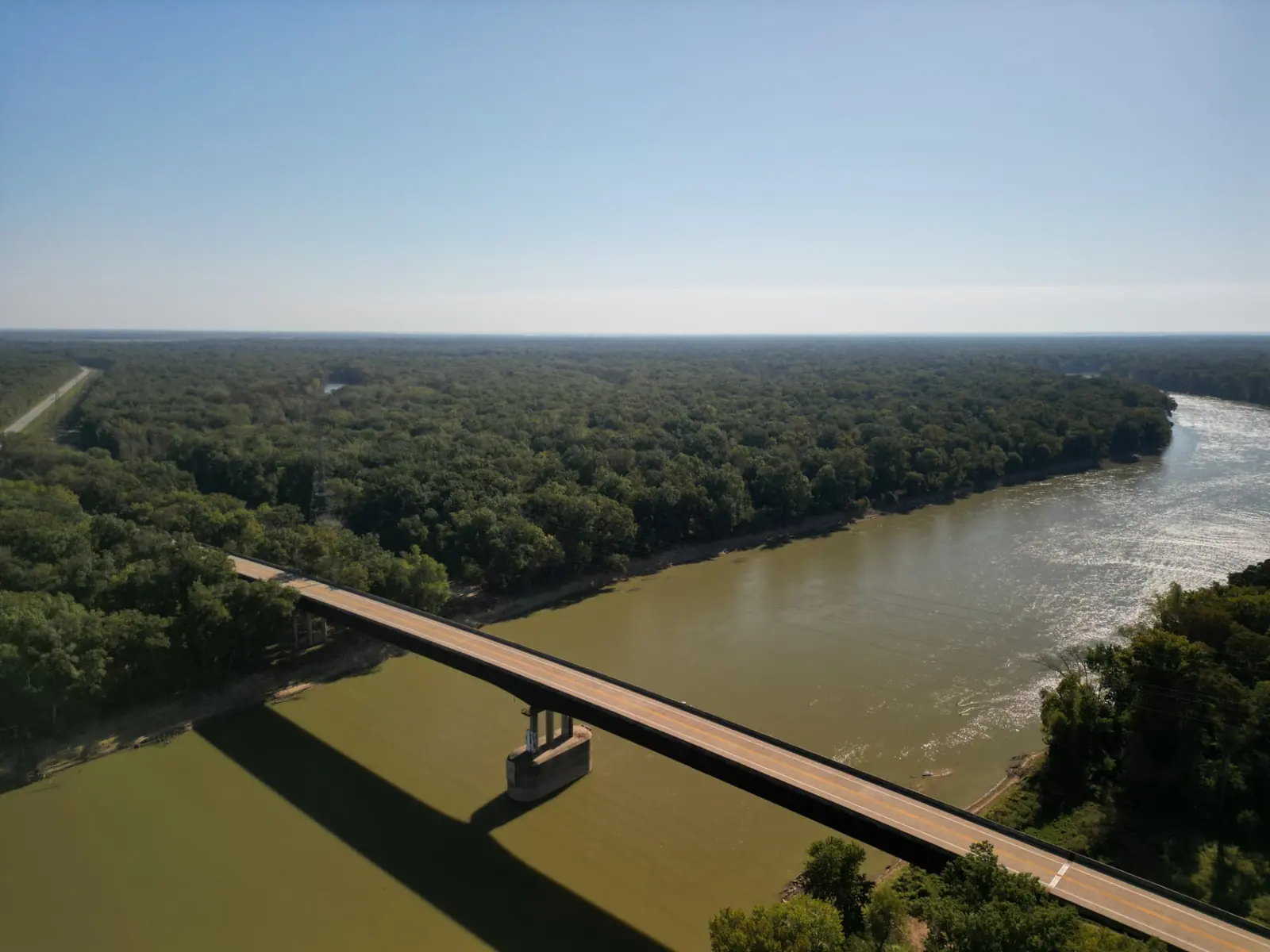 Aerial view of a long bridge crossing the river, the far side out of sight